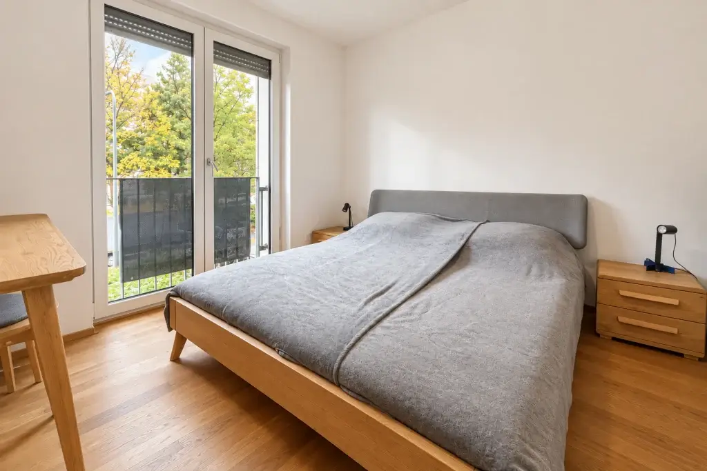 Schlafzimmer mit Doppelbett, Holzboden und bodentiefer Fenstertür in der Wohnung in Frankfurt-Gallus