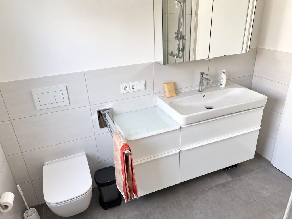 Modernisiertes Badezimmer mit Waschtischunterschrank, Spiegelschrank und wandhängendem WC