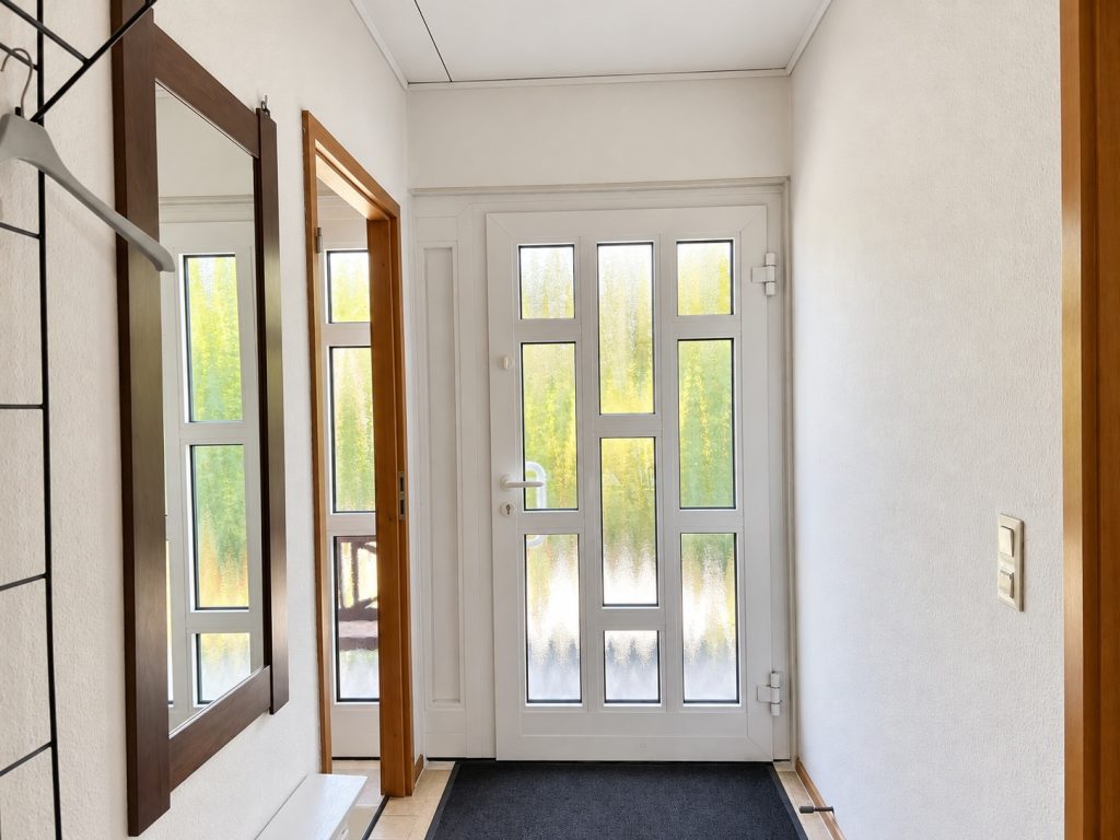 Eingangsbereich mit verglaster weißer Haustür, Garderobe und Wandspiegel