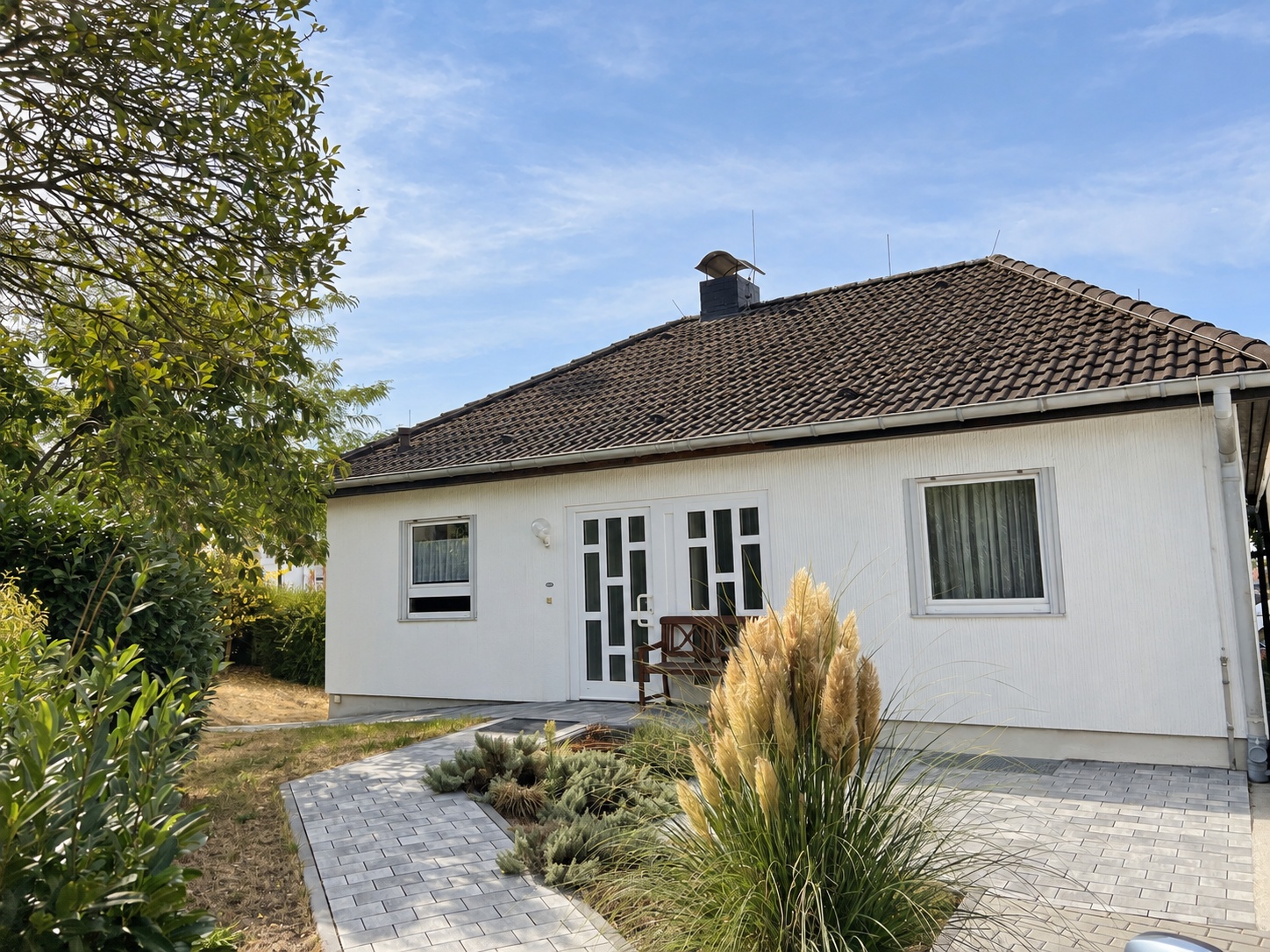 Eingangsseite des freistehenden Bungalows in Hofheim-Wallau mit gepflastertem Zugang und bepflanztem Vorgarten
