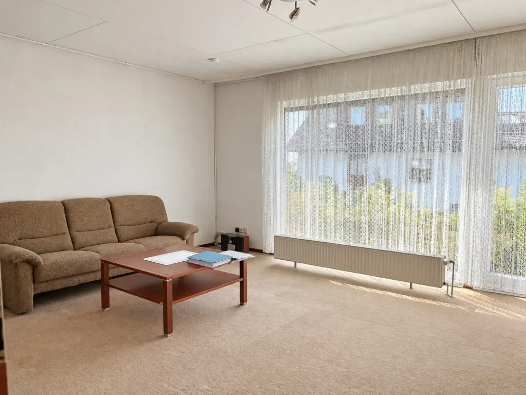Wohnzimmer mit großer Fensterfront zum Garten, Sofa und Couchtisch